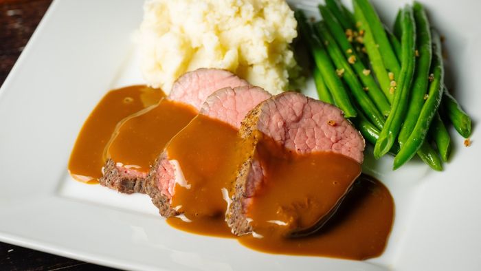 Gravy drizzled over tender meat, paired with creamy mashed potatoes and green beans.