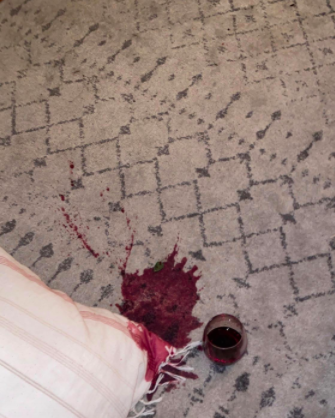 a light gray rug with a red wine spill on it