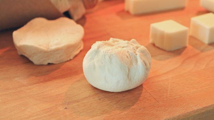 A biscuit ball placed next to cheese cubes and biscuit dough.