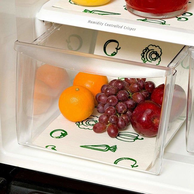 an open fridge with a drawer containing a liner beneath oranges, grapes, and apples