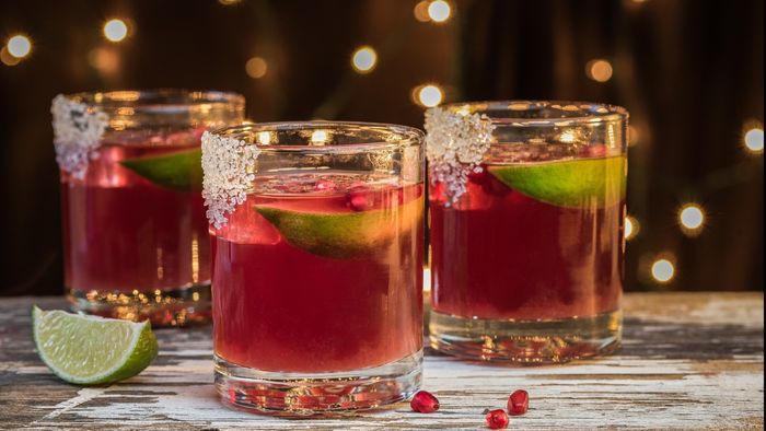 Three glasses of a pomegranate cocktail elegantly arranged on a table.