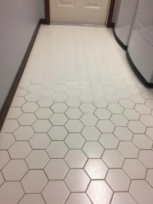 A tiled floor where half the grout appears dark and dirty, while the other half is clean and white.
