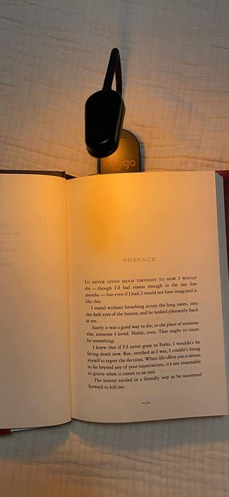 An amber clip-on light being used for reading a book at night.