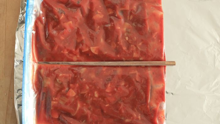A bag of tomato sauce with a chopstick placed in the center.