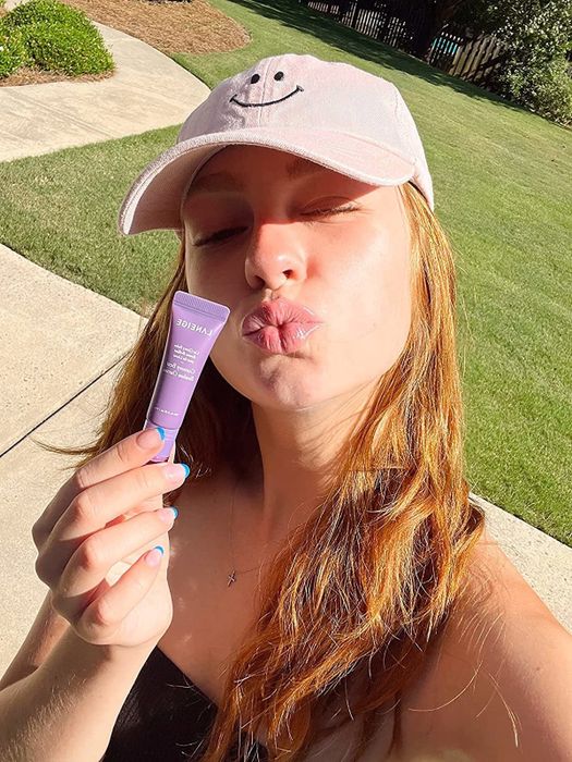 A reviewer holding the glowy lip balm