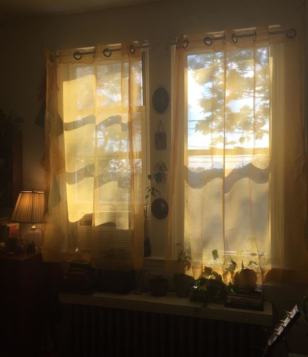 Sheer white curtains in a window, with light streaming through them.
