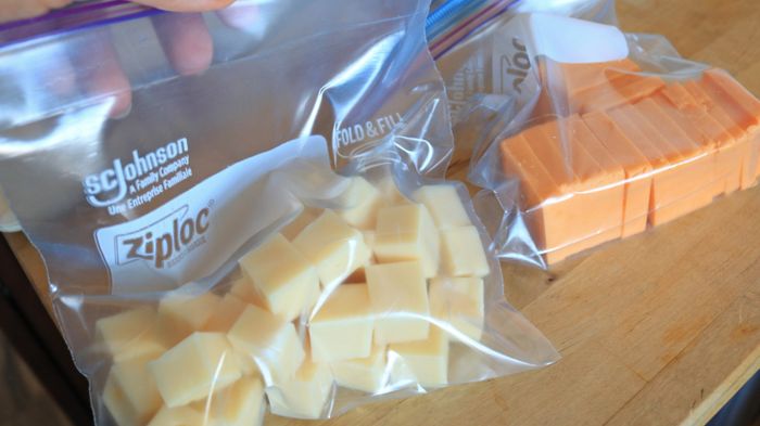 White cheese cubes and yellow cheese slices neatly packed in separate zip-top bags.
