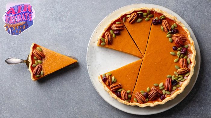A pumpkin pie with a slice cut and placed on a spatula.