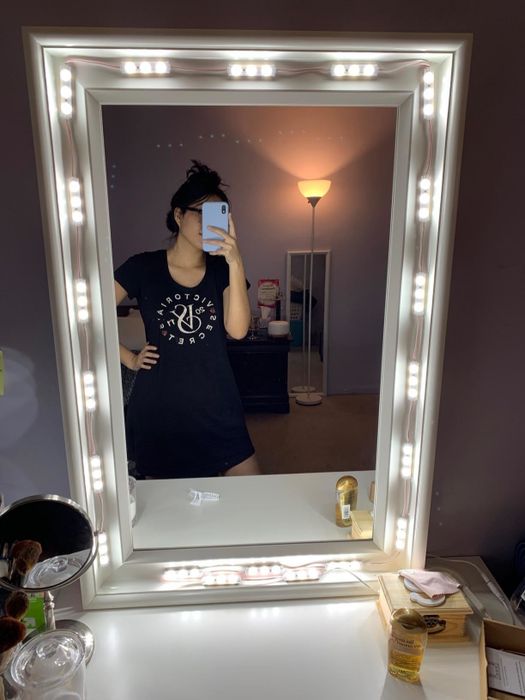 A reviewer's photo of themselves reflected in the vanity mirror, enhanced with light strips around the edges.
