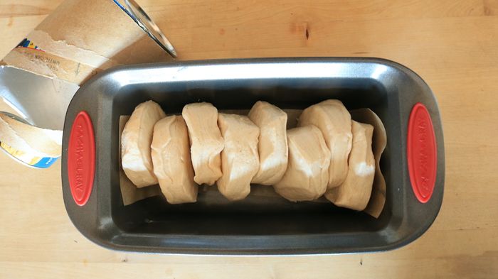 Uncooked biscuits arranged in a loaf pan.