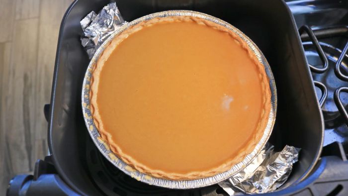 A pumpkin pie placed inside an air fryer basket.