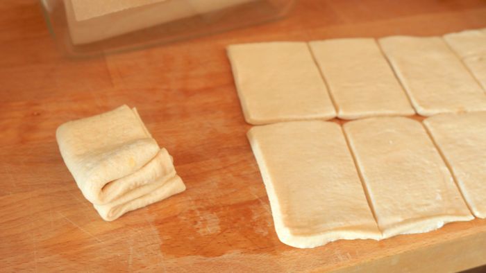 Small dough rectangles laid out on a cutting board.