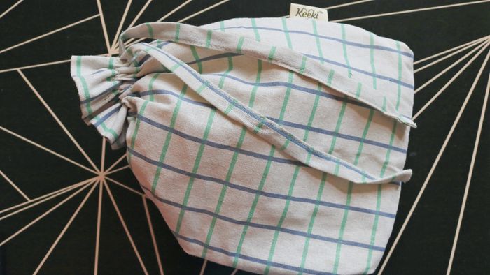 A black table showcasing a fabric drawstring bag designed for storing bread.