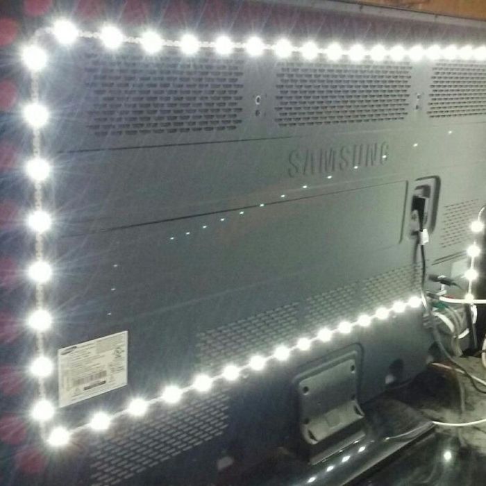 The backside of a Samsung TV, with LED strip lights outlining the edges, and various cables plugged into the TV.