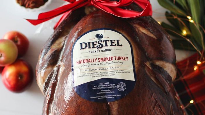 A beautifully smoked turkey, adorned with a bow, elegantly placed on a table.