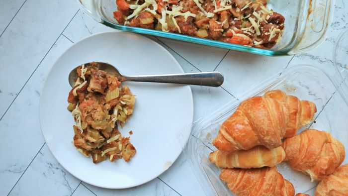 A generous scoop of stuffing placed beside a pack of croissants on a kitchen counter.