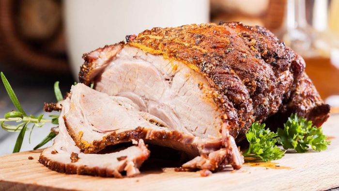 A roast pork shoulder rests on a cutting board.