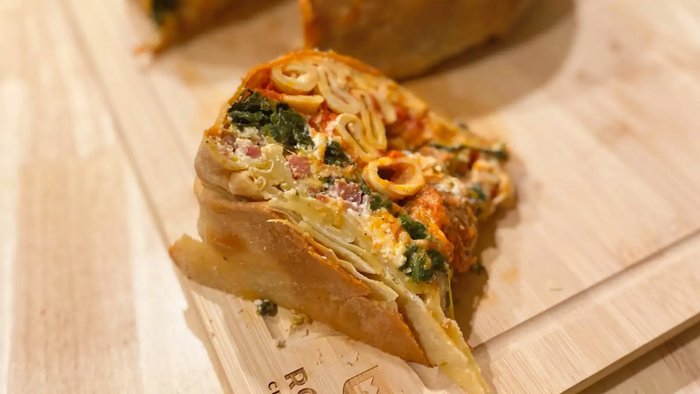 A slice of layered Timpano resting on a cutting board.