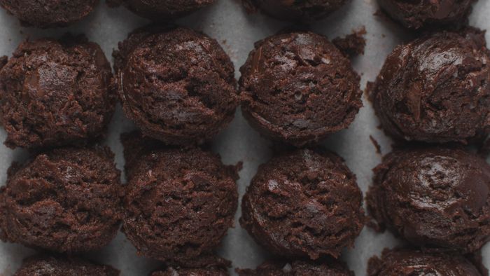 Chocolate cookie dough balls arranged on a baking tray.