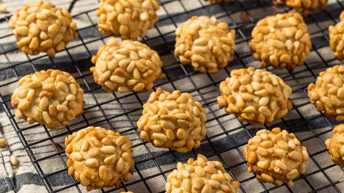 Pignoli cookies resting on a cooling rack.