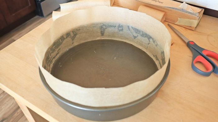 A cake pan with parchment paper lining its sides.