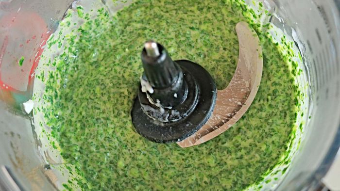 A food processor filled with a spinach mixture.