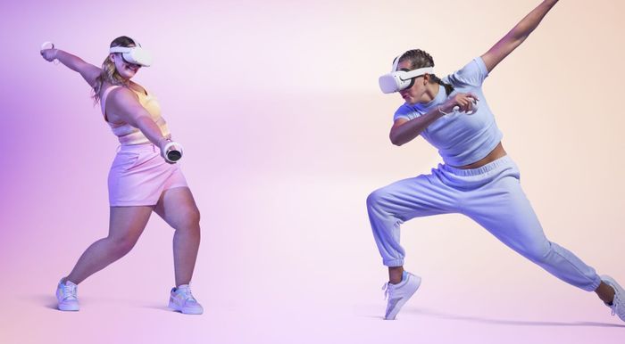 Two people in action poses, both wearing the white headset over their eyes.