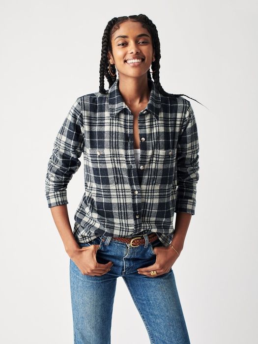 A model wearing a blue and cream flannel tucked into blue jeans.