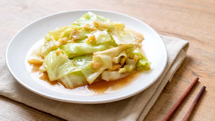 Thai-style cabbage seasoned with fish sauce, presented on a table with chopsticks.