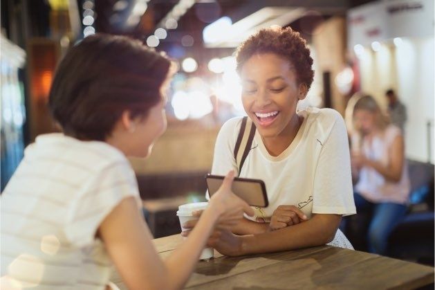 Two people conversing, one showing the other something on their phone screen