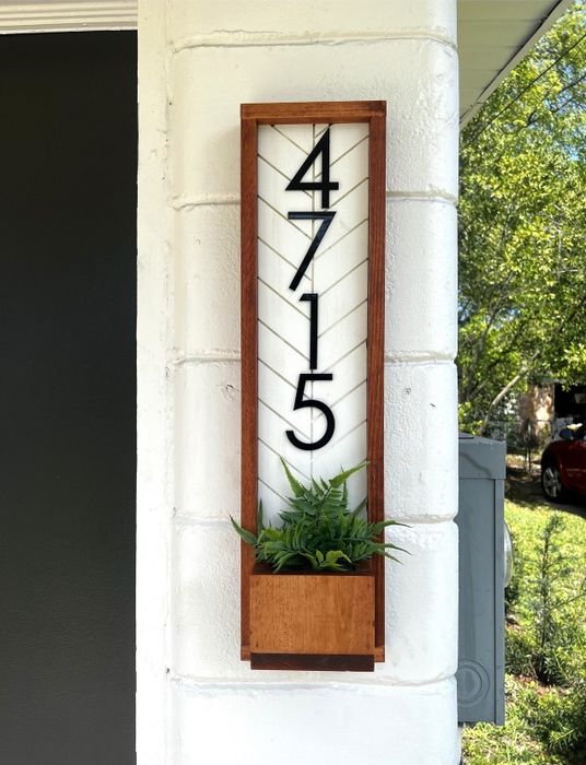 A house number sign with bold numerals, featuring a built-in planter underneath