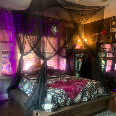 A dark, goth-inspired room with a black canopy hanging over the bed, adding a touch of mystery.