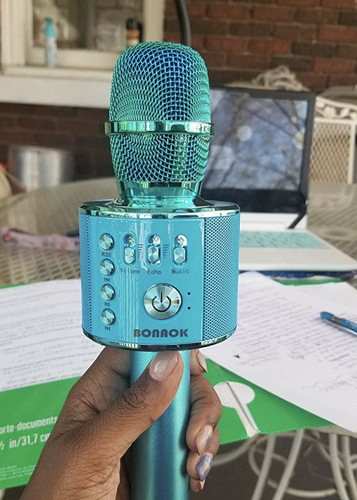 Reviewer holding a blue karaoke microphone with buttons