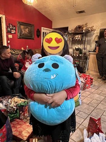 a reviewer cuddling the Sully Squishmallow