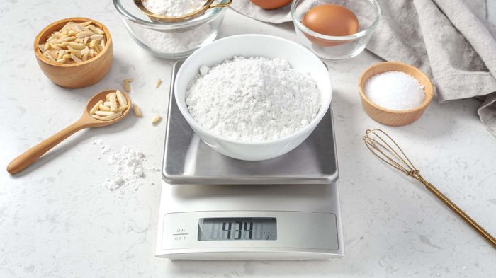 A kitchen scale with a bowl of flour placed on top.