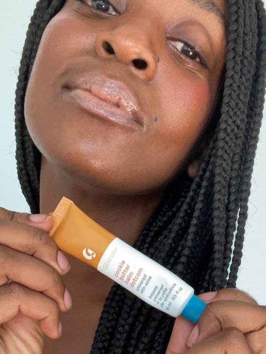 A model applying the lip balm and holding the tube in hand