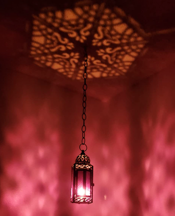 An ornate lantern hanging, casting beautiful, intricate shadows on the wall, adding an atmospheric touch to any room.