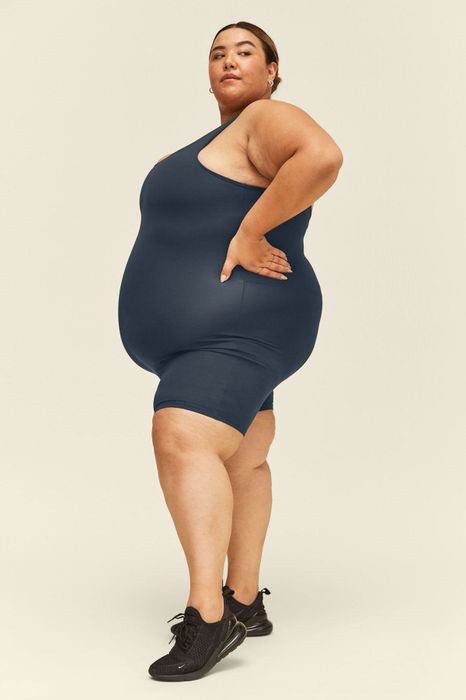 A model confidently wearing the unitard in a rich midnight blue.