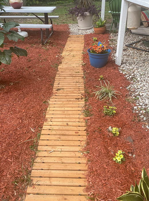 A customer photo showing the wooden pathway laid out in a garden, bordered by wood chips