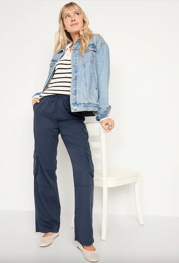 The model wears a denim jacket, a striped top, cargo pants, and flats for a laid-back yet fashionable look.
