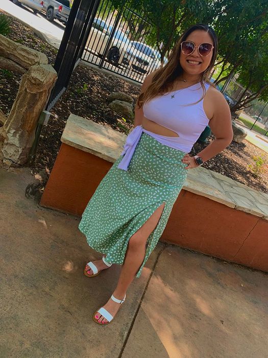 A reviewer in a white top and a polka-dot skirt paired with white sandals, posing on a sidewalk