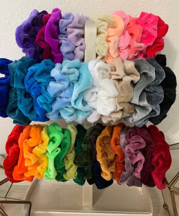 A display stand showing various colorful velvet scrunchies.