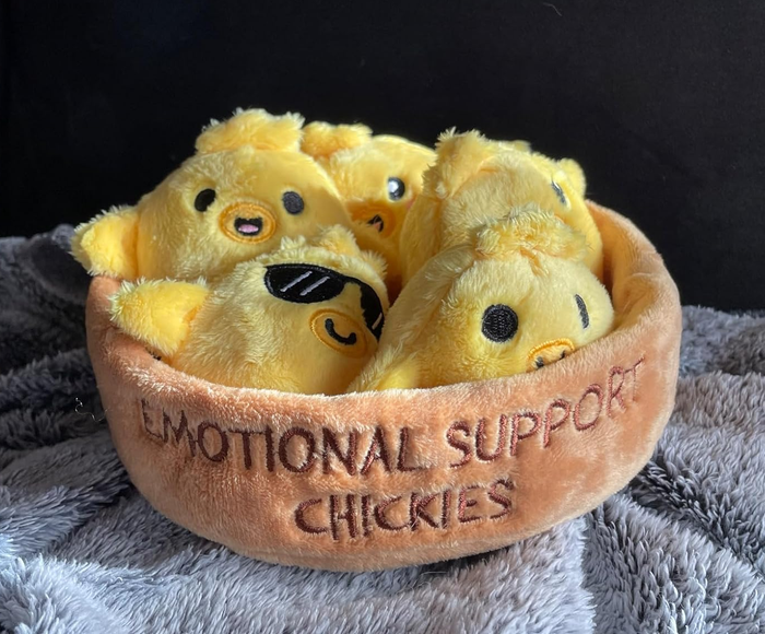 Plush toy chicks nestled in a soft, round bed with 