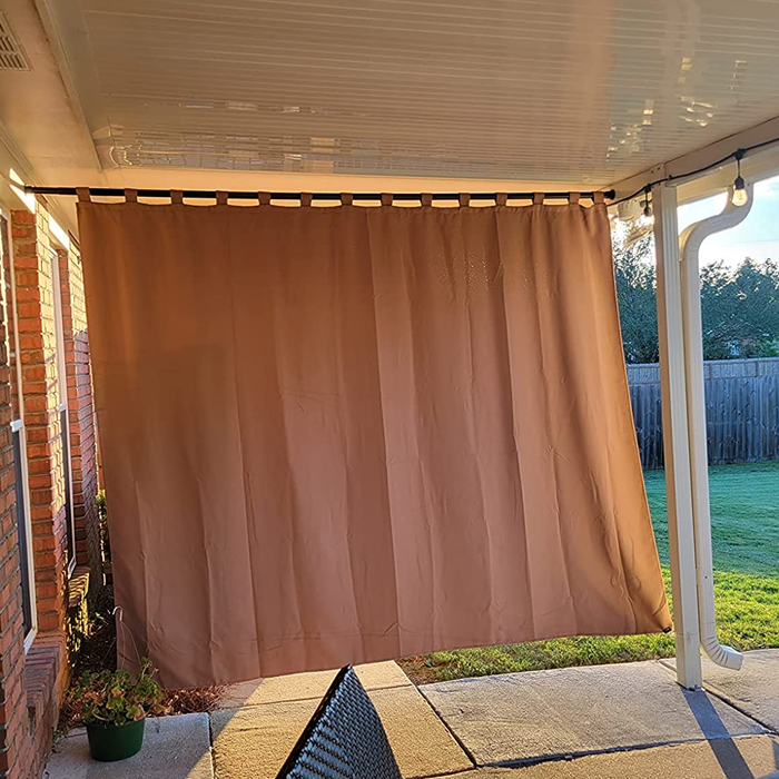 A photo from a reviewer showing the curtain installed on a back patio, providing shade by blocking the sun