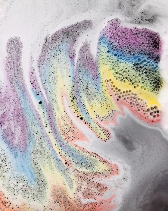 a reviewer showing rainbow-colored soapy water in a bath