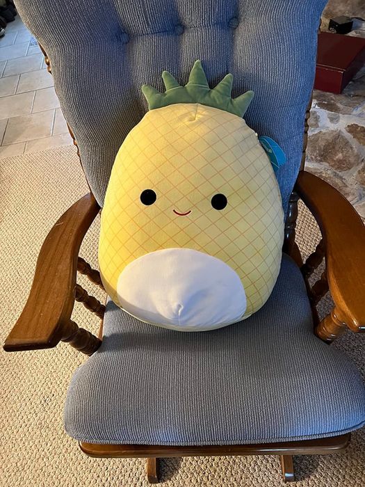 a pineapple Squishmallow resting on a chair