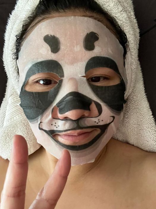 a reviewer wearing a panda sheet mask
