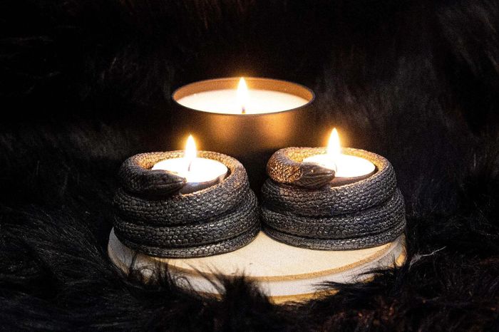 Snake-shaped tea light holders surrounding small lit candles, creating a cozy ambiance