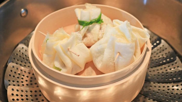 Dumplings inside a steamer basket within a pot.