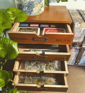 A wooden storage organizer with labeled drawers, ideal for keeping sewing supplies and cards neatly stored and easy to access.